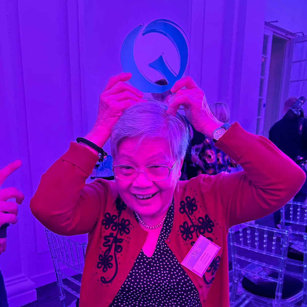 Yok Chan in red cardigan with award on her head