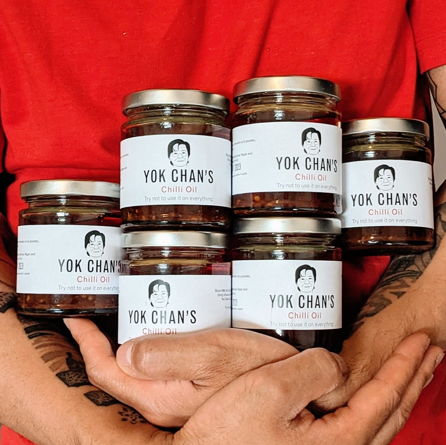 Person holding six jars of Yok Chan's Chilli Oil