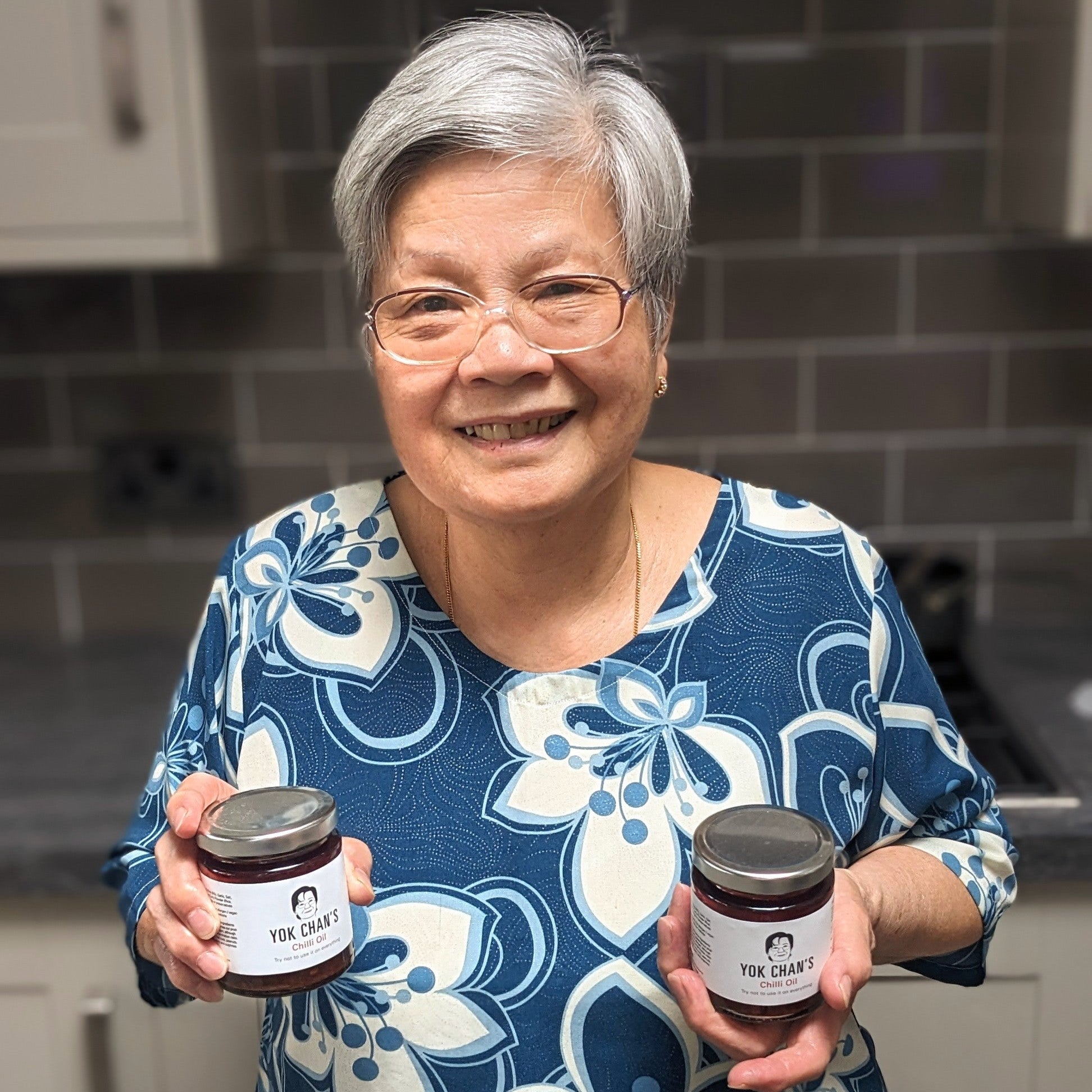 Yok Chan in her kitchen with chilli oil jars