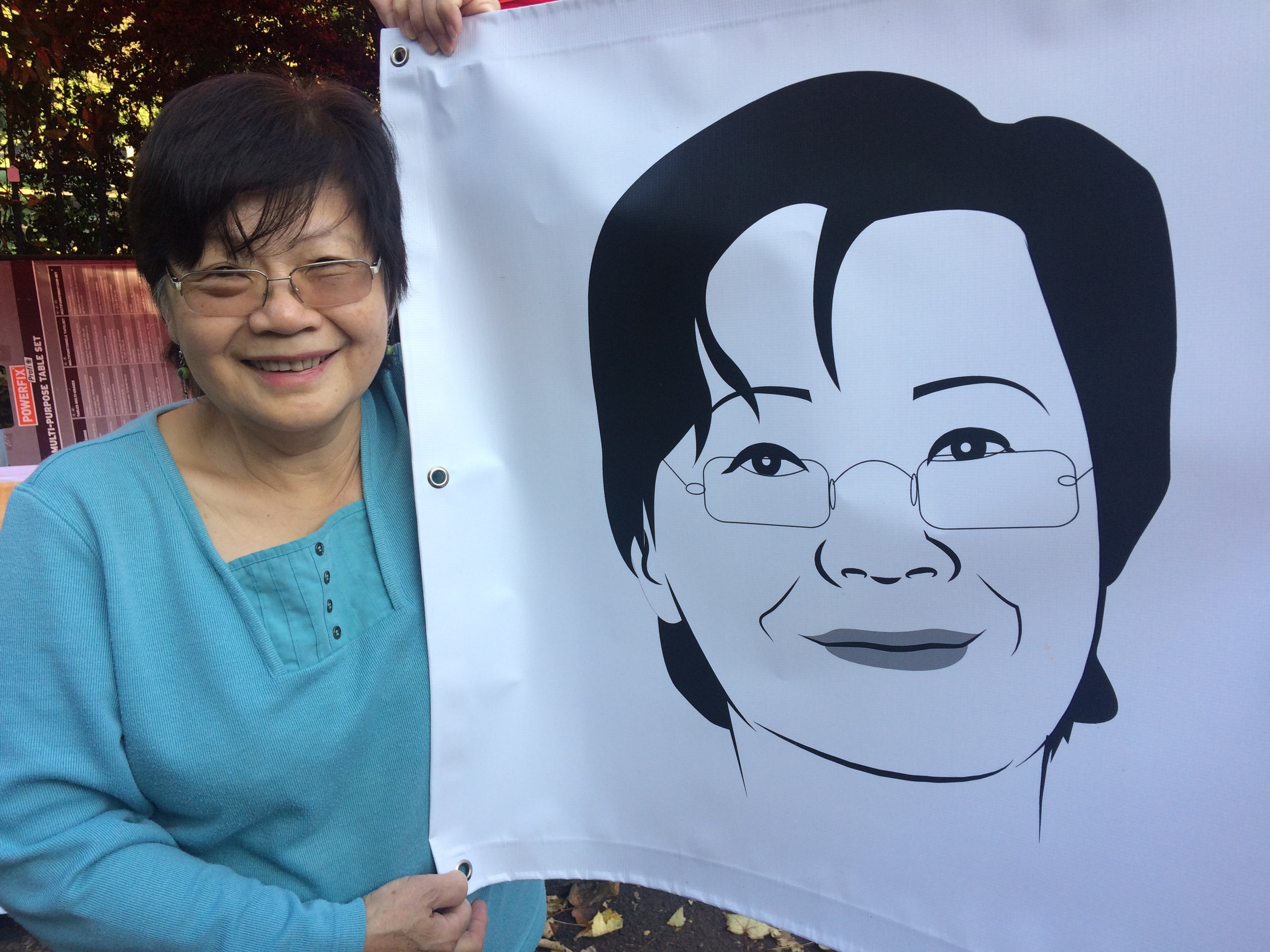 Yok Chan holding a banner with her face on it